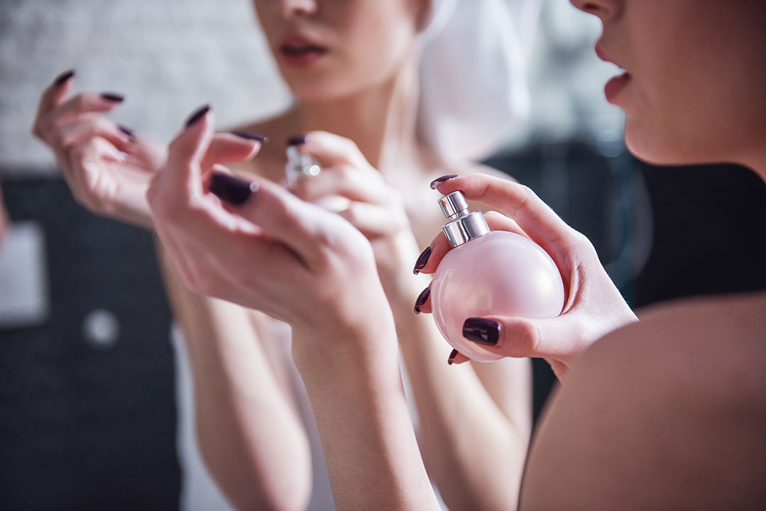 Mujer aplicando perfume en mano